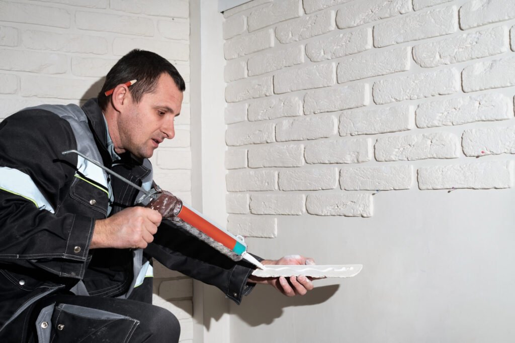 Master applies glue tiles for facing the house. The master builder decorates the walls of the apartment. Finishing the building with modern materials.
